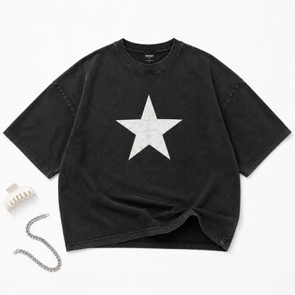 Model wearing Stellar Star oversized washed black t-shirt with distressed white star graphic on outdoor crosswalk flat