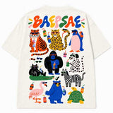 Back view of an off-white oversized t-shirt with a colorful 'BAEPSAE' logo and a jumbo graphic print of cartoon animals (tiger, leopard, penguin, gorilla, cat, zebra, flamingo, bear, turtle) wearing sunglasses and holding drinks, displayed on a clean white background.