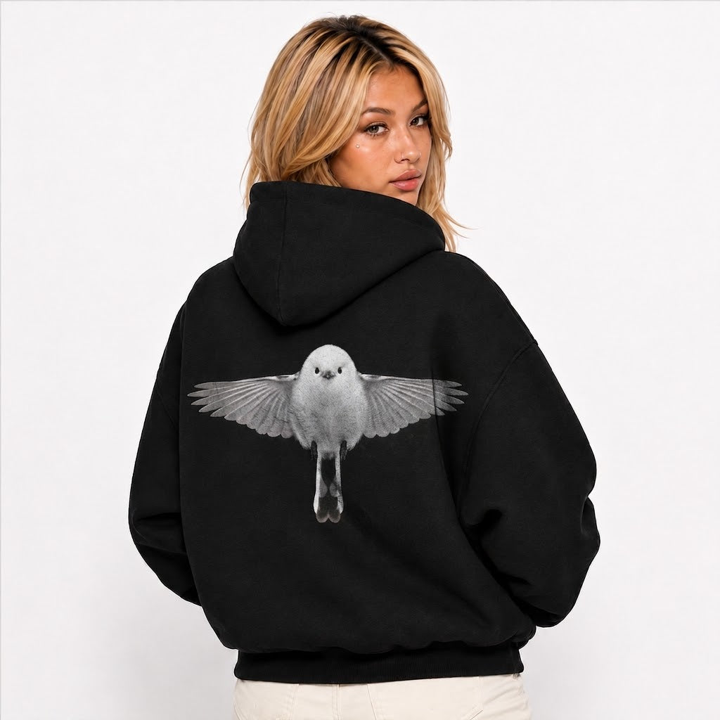 A woman wearing a black pullover hoodie, viewed from the back. The hoodie features a large graphic print of a white bird with spread wings on the center back.